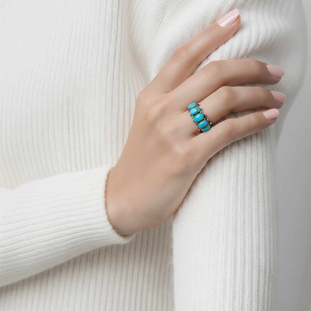 Hand wearing a turquoise ring on a white background